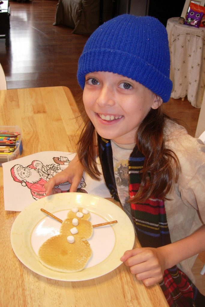 little girl eating snowman shaped pancakes