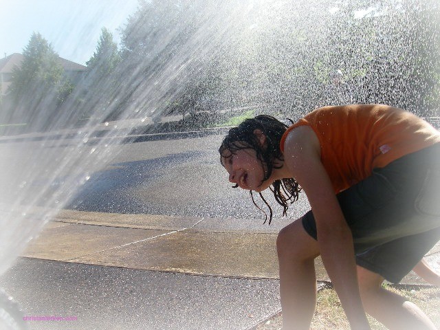 little girl laughing in the sprinklers