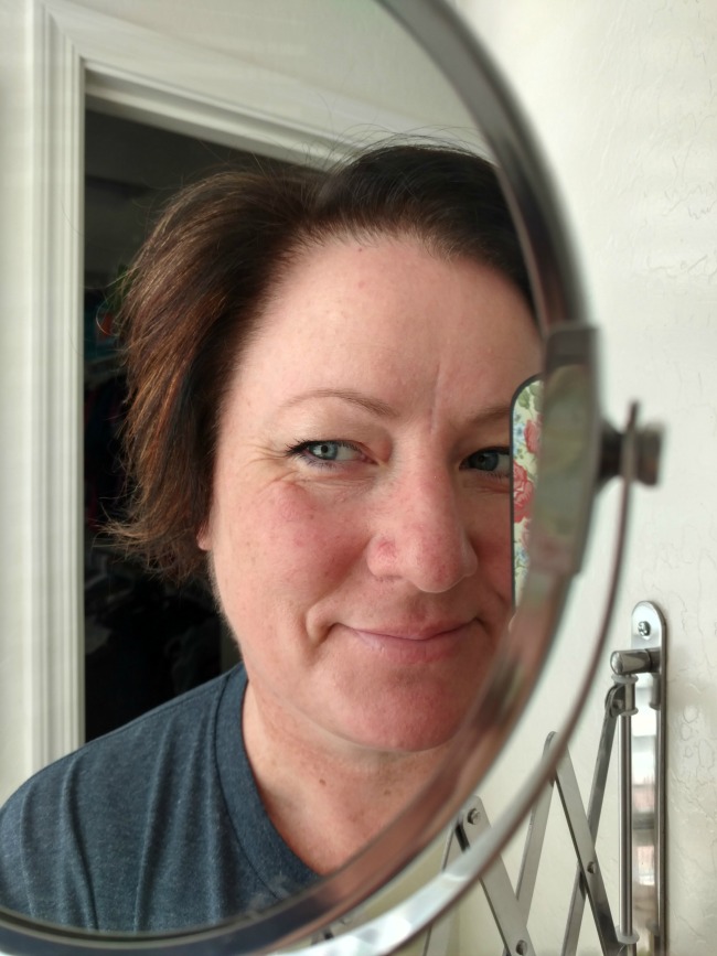 makeup free woman smiling at the mirror