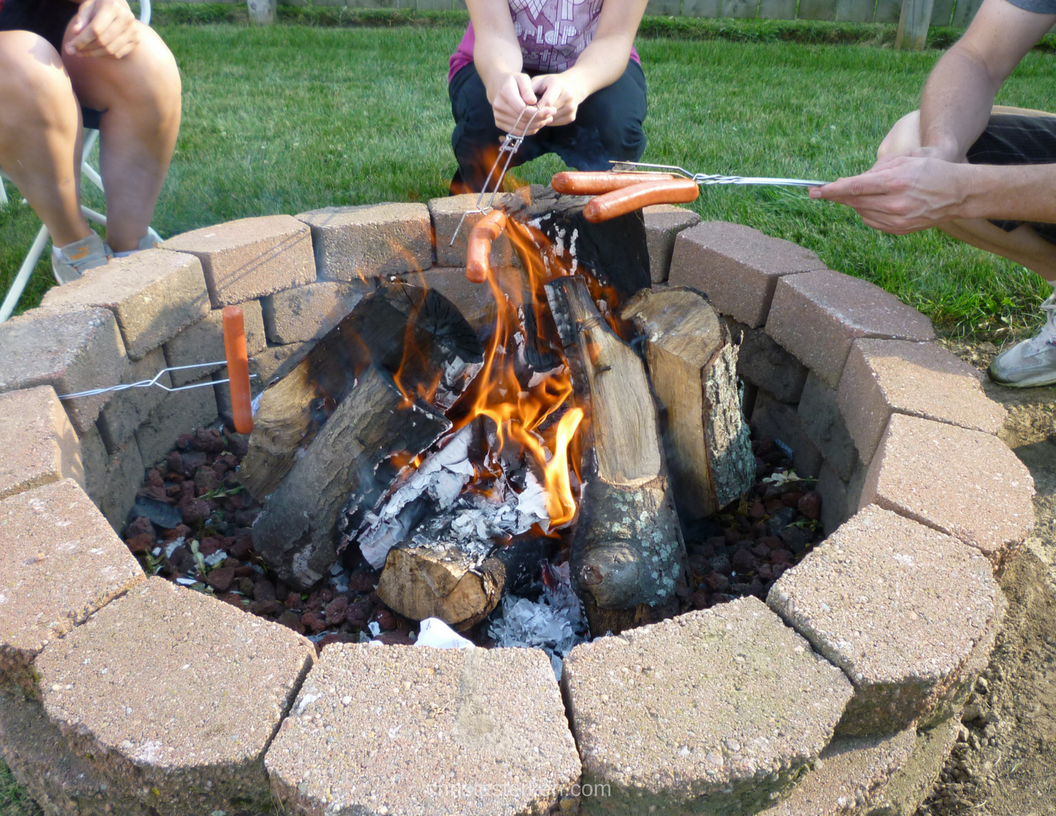 family roasting hotdogs over a firepit