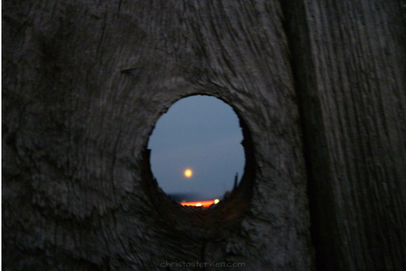 seeing a full moon through a fence knothole