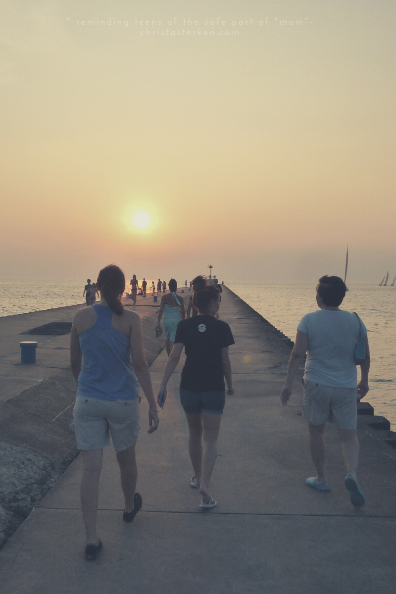 mother and daughters walking on dock towards sunset