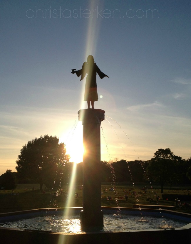 angel statue with sun setting behind 