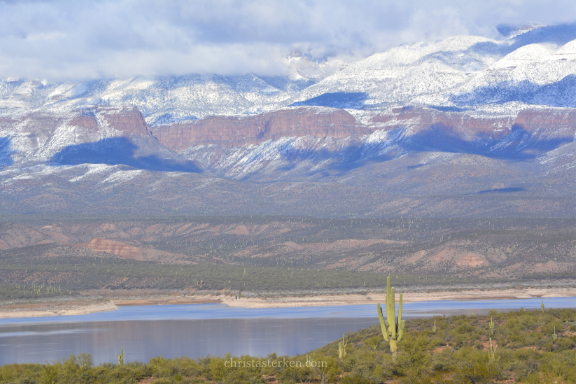 snow on mountains behind lake