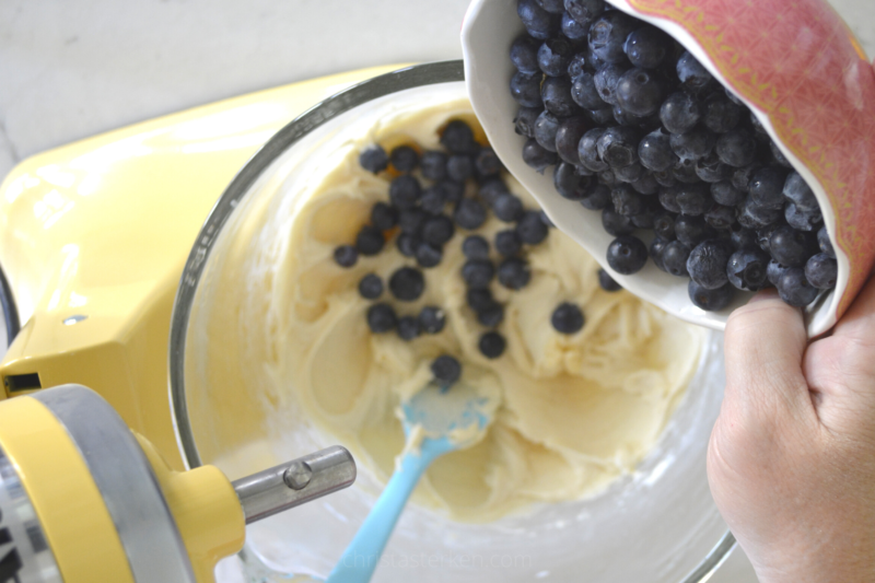 pouring blueberries into batter in mixing bowl