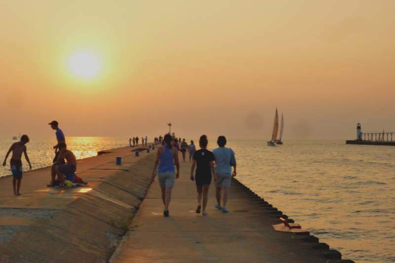 father and daughters walking on a pier towards setting un